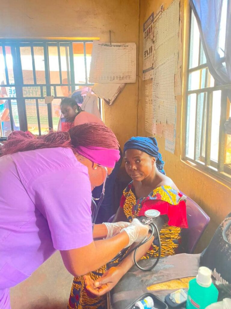 A community health worker attends to an older woman during a screening.
