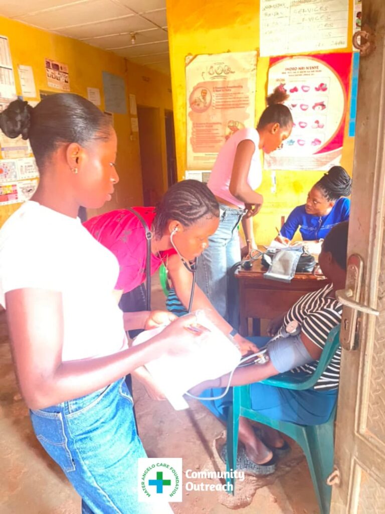 A healthcare worker attends to a seated community member during a screening activity.
