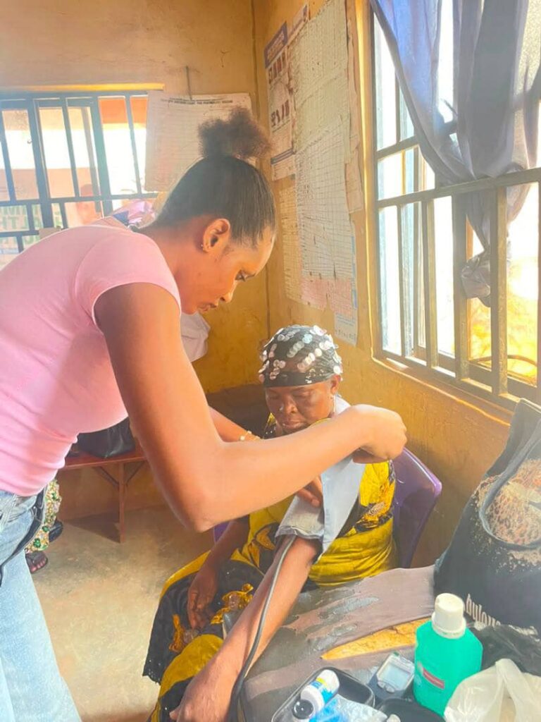A healthcare worker takes a blood pressure measurement from an older woman.