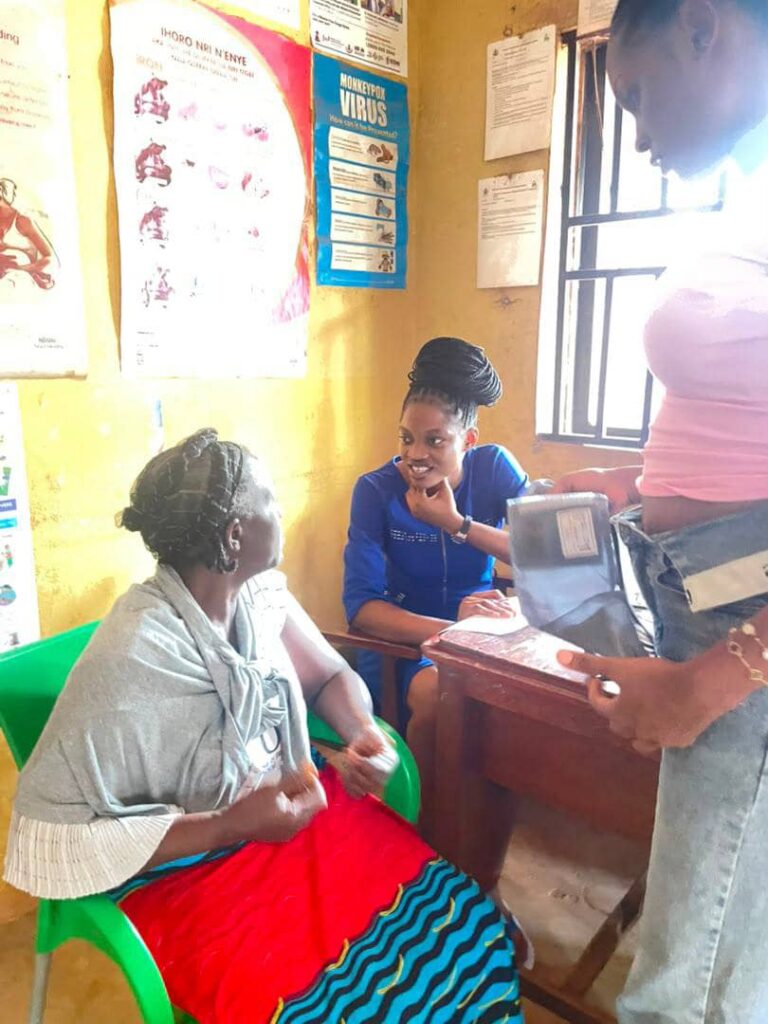 A community healthcare worker speaks with a seated woman during the outreach.
