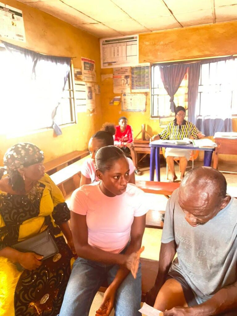 Community members sit together during the healthcare outreach at Ugbowa Health Centre.